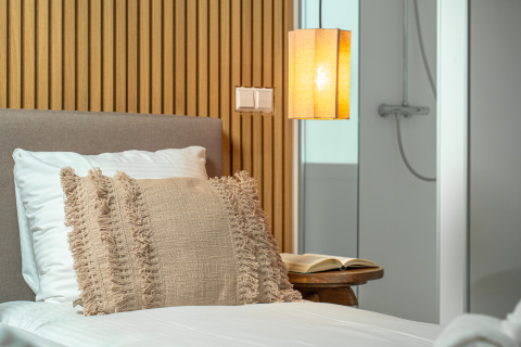 Modernes Schlafzimmer im Wellness Lodge im Holiday Park De IJsvogel, gemütlich beleuchtet neben Bad.