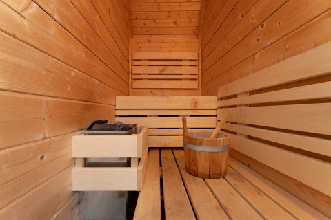 Interno di una sauna in legno con panca e secchio, Wellness Lodge, Holiday Park De IJsvogel, Paesi Bassi.