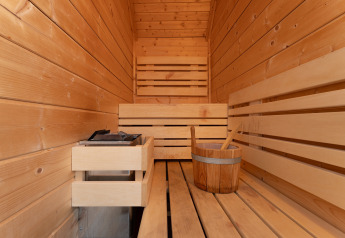 Interior of a wooden sauna with bench and bucket, Wellness Lodge, Holiday Park De IJsvogel, Netherlands.