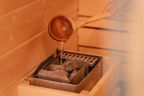 Versare acqua sulle pietre calde della sauna al Wellness Lodge di Holiday Park De IJsvogel, Paesi Bassi.