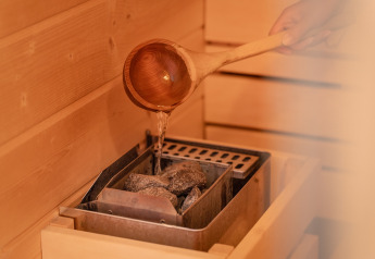 Versare acqua sulle pietre calde della sauna al Wellness Lodge di Holiday Park De IJsvogel, Paesi Bassi.