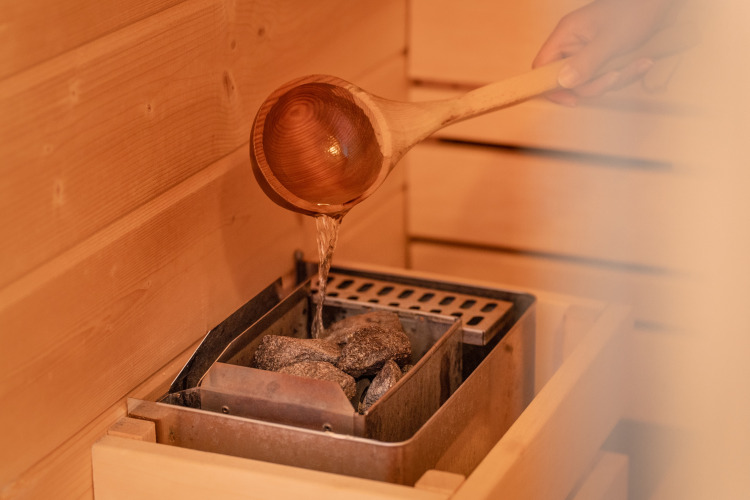 Vertiendo agua sobre piedras calientes de la sauna en Wellness Lodge, Holiday Park De IJsvogel, Países Bajos.