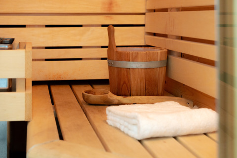 Interno di una sauna con secchio di legno, mestolo e asciugamano al Wellness Lodge, Holiday Park De IJsvogel, Paesi Bassi.