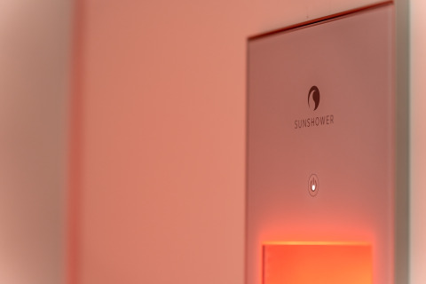 Close-up of a Sunshower device glowing softly in a wellness-themed tiny house at De IJsvogel, Netherlands.