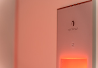 Nærbillede af en Sunshower-enhed med blødt orange lys i et wellness tiny house ved De IJsvogel, Holland.