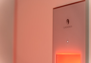 Primer plano de un dispositivo Sunshower con luz cálida en una tiny house wellness en De IJsvogel, Países Bajos.