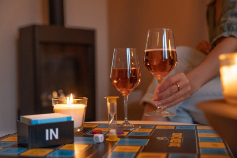 Board game and wine glasses by candlelight in a cozy Wellness Lodge at Holiday Park De IJsvogel, Netherlands.