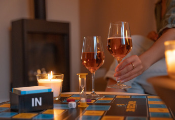 Juego de mesa y copas de vino junto a velas en una Wellness Lodge del Holiday Park De IJsvogel, Países Bajos.