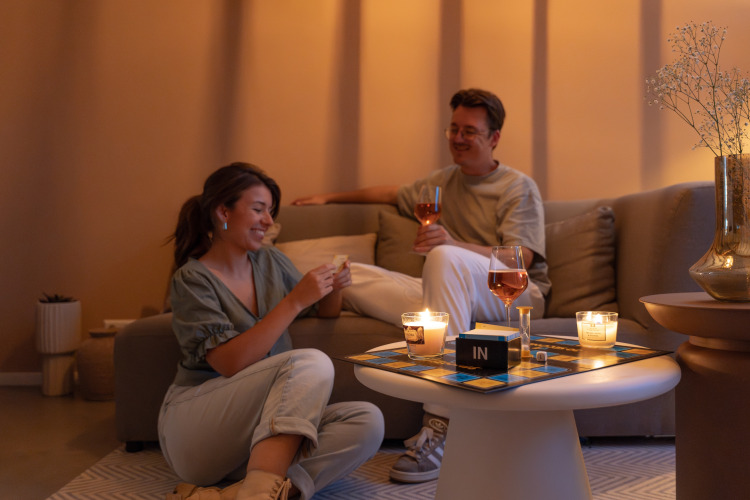 Twee personen genieten van een bordspel en wijn in het kaarslicht in de Wellness Lodge, De IJsvogel, Nederland.