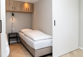 Modern bedroom with a single bed, nightstand, and storage in Berg Lodge - Sauna at Resort Mooi Bemelen, Netherlands.