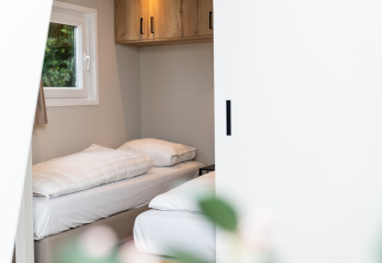 Bright bedroom with single beds and window at Berg Lodge - Sauna, Resort Mooi Bemelen in the Netherlands.