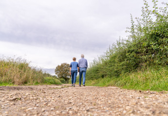 Two people walk along a country path at Berg Lodge - Sauna at Resort Mooi Bemelen in the Netherlands.