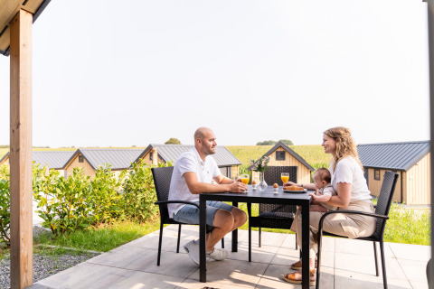 Familie nyder morgenmad udendørs ved Berg Lodge - Sauna på Resort Mooi Bemelen i Holland.