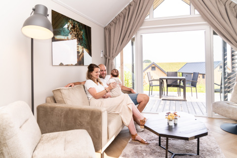Famille se détendant dans le salon de Berg Lodge - Sauna au Resort Mooi Bemelen, Pays-Bas, vue sur la terrasse.