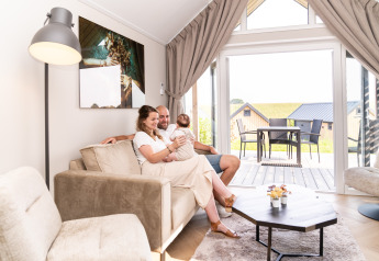 Famille se détendant dans le salon de Berg Lodge - Sauna au Resort Mooi Bemelen, Pays-Bas, vue sur la terrasse.