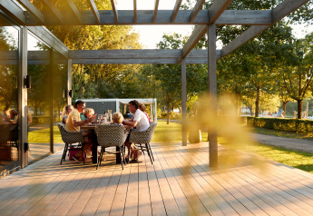 Eine Familie genießt eine Mahlzeit auf einer Holzterrasse bei einer Glamping-Unterkunft im Grünen.