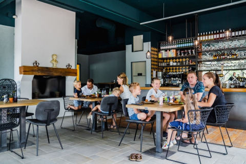 Gezinnen genieten samen van een maaltijd in een gezellig restaurant met modern interieur bij glamping.