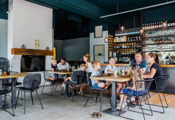 Familien essen gemeinsam in einem gemütlichen Restaurant mit moderner Einrichtung in einer Glamping-Anlage.