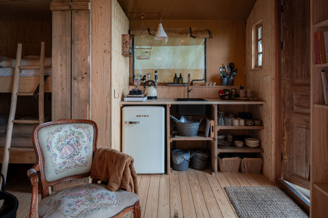 Intérieur de la tente safari Smûk Tent Huske avec cuisine, petit frigo et lits superposés chez Smûk Recreatie.