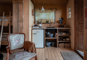 Interno della tenda safari Smûk Tent Huske con cucina accogliente, frigo e letti a castello a Smûk Recreatie.