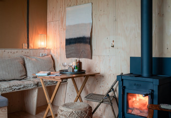 Gezellige binnenkant van safari tent Smûk Tent Huske bij Smûk Recreatie met houtkachel en houten wanden.