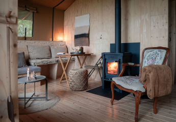 Knus interieur van een safaritent met houtkachel bij Smûk Tent Huske in Nederland.