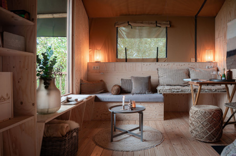 Knus interieur van safaritent met lichte houten panelen en zithoek bij Smûk Tent Huske in Nederland.