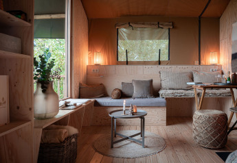 Interno accogliente di tenda safari con legno chiaro e area salotto presso Smûk Tent Huske nei Paesi Bassi.