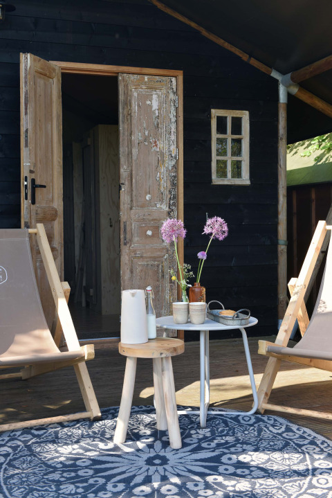Coin salon extérieur rustique avec chaises, tables et fleurs au Smûk Tent Huske, Smûk Recreatie, Pays-Bas.