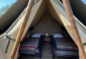Tienda safari con dos camas individuales y suelo de madera en Camping Seasonova Les Marguerites, Francia.