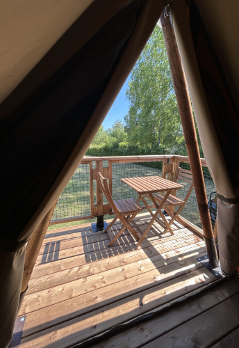 Uitzicht vanuit een safaritent bij SLOW LIFE VERBLIJF op Camping Seasonova Les Marguerites, houten terras met tafel.