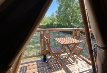 Vista desde una tienda safari en SLOW LIFE VERBLIJF, Camping Seasonova Les Marguerites, terraza de madera con mesa.