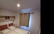 Dormitorio en una cabaña de Camping Floreal La Roche-en-Ardenne, Bélgica, con cama doble y estanterías.