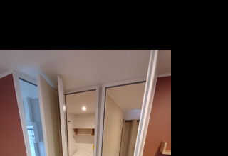 Interno di un cottage al Camping Floreal La Roche-en-Ardenne con letto, divano e arredo moderno.