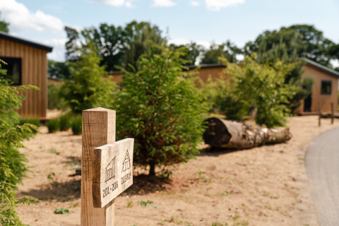 Holzschild mit Zimmernummern vor einem Sand Lodge Tiny House im Holiday Park De IJsvogel, Niederlande.