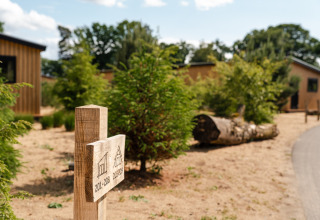 Houten wegwijzer met huisnummers bij Sand Lodge tiny house in Holiday Park De IJsvogel, Nederland, in de zomer.