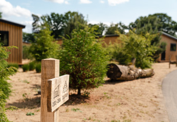Houten wegwijzer met huisnummers bij Sand Lodge tiny house in Holiday Park De IJsvogel, Nederland, in de zomer.
