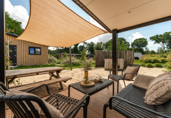 Area esterna alla Sand Lodge Jacuzzi, Holiday Park De IJsvogel, Olanda, con tenda ombreggiante e sedie.