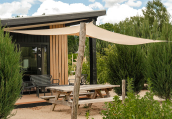 Mesa de picnic exterior y toldo frente a la tiny house Sand Lodge Sauna en Holiday Park De IJsvogel, Países Bajos.