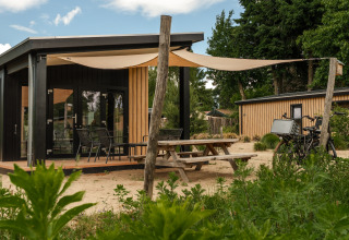Tiny House Sand Lodge Sauna im Holiday Park De IJsvogel, Niederlande, mit Terrasse und Fahrradparkplatz.