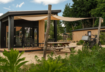 Tiny House Sand Lodge Sauna im Holiday Park De IJsvogel, Niederlande, mit Terrasse und Fahrradparkplatz.