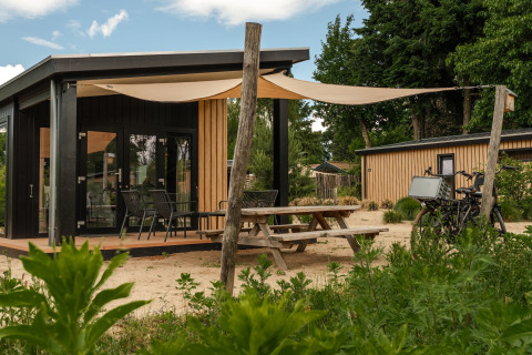 Sand Lodge Sauna tiny house ved Holiday Park De IJsvogel i Holland, med terrasse og cykelparkering.