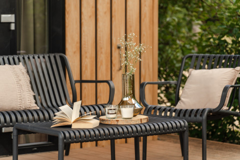 Gezellige zithoek buiten bij Sand Lodge Sauna, Holiday Park De IJsvogel, met zwarte stoelen en tafel.