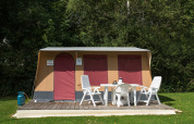 Tenda safari Comforttent al Camping Floreal La Roche-en-Ardenne in Belgio con mobili da giardino bianchi.