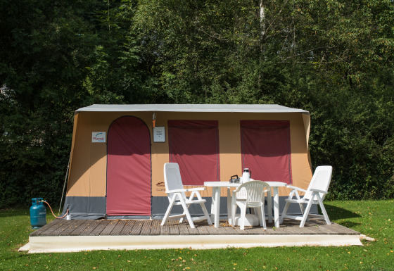 Tenda safari Comforttent al Camping Floreal La Roche-en-Ardenne in Belgio con mobili da giardino bianchi.