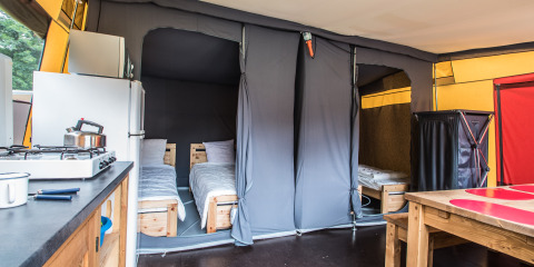 Interno della tenda safari Comforttent al Camping Floreal La Roche-en-Ardenne con letti e cucina.