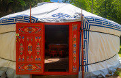 Yurt med farverig dekoreret dør og traditionelle motiver ved Camping Des Randonneurs i Frankrig, omkranset af skov.