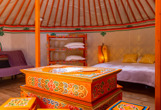 Interior de una yurta en Camping Des Randonneurs en Francia, con muebles coloridos y decoración acogedora.