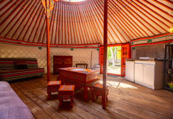 Inde i en traditionel yurt med farverigt dekorerede møbler og trægulv i Camping Des Randonneurs, Frankrig.