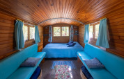 Interno della Gipsy wagon al Camping Des Randonneurs, Francia, con pareti in legno e divani azzurri.